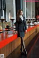 A woman in a business suit standing at a bar.