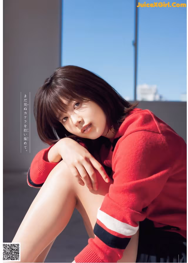 A woman in a red sweater sitting on a window sill.