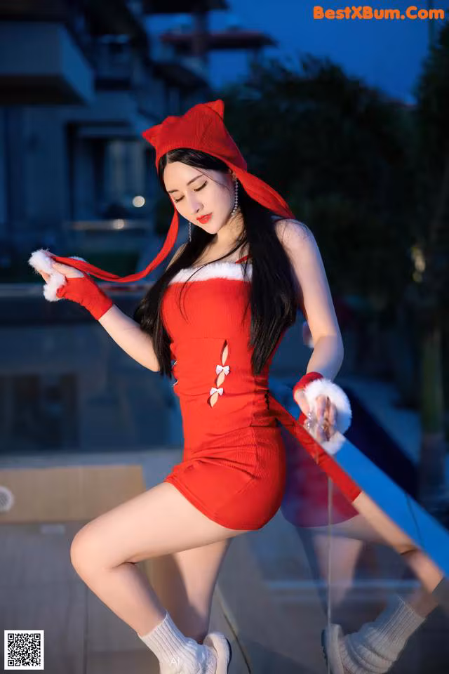 A woman in a red dress and hat posing for a picture.