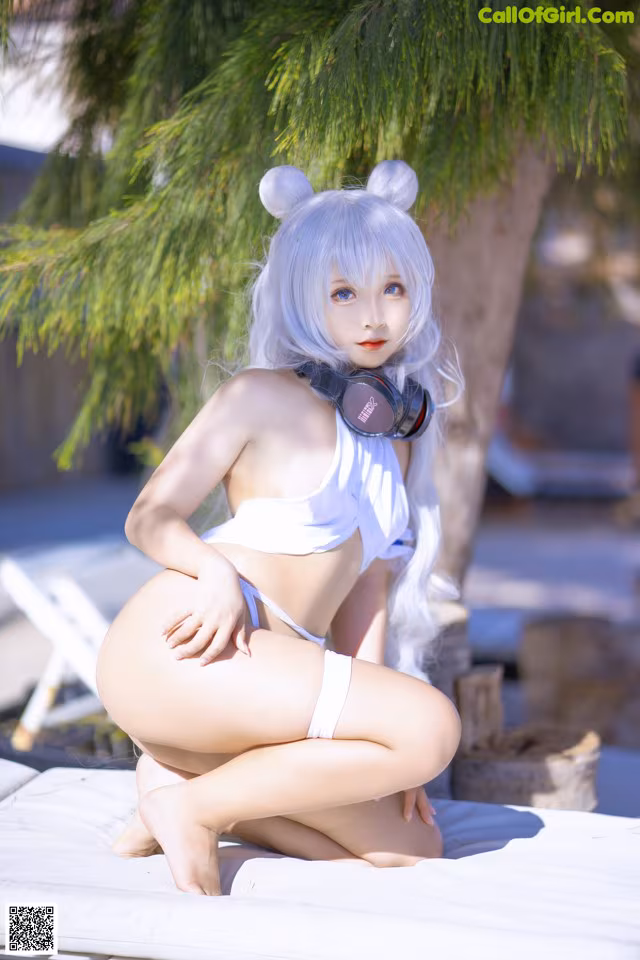 A woman in a white bikini sitting on a lounge chair.