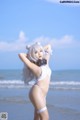 A woman in a white bikini standing on the beach.