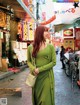 A woman in a green dress is walking down the street.