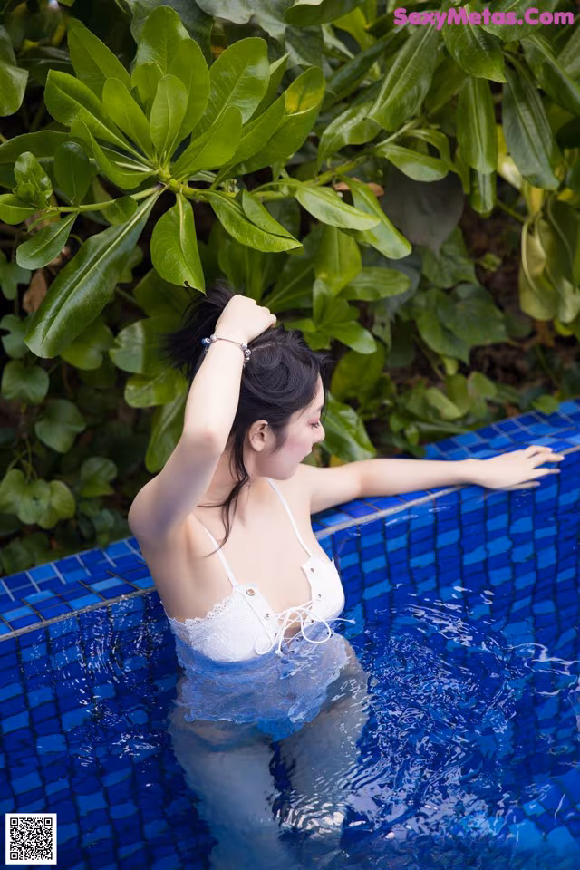 A woman in a white bikini standing in a pool.