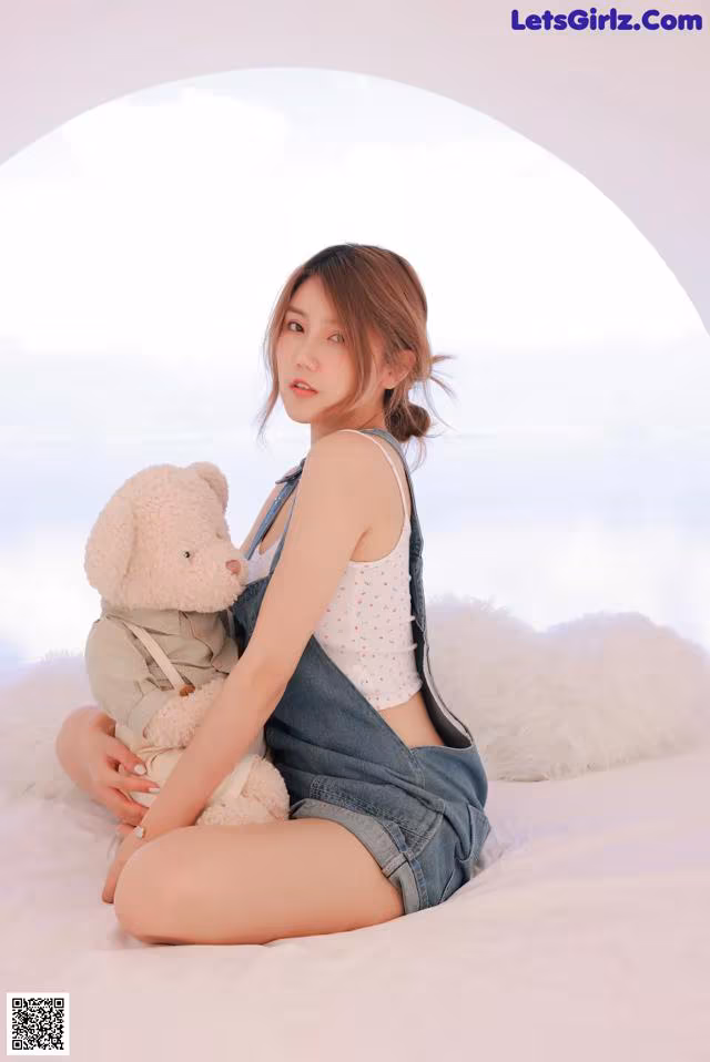 A woman sitting on a bed holding a teddy bear.