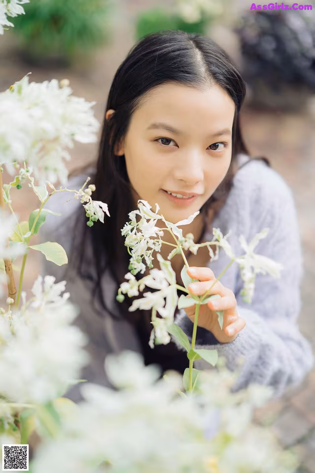 A young woman holding a bunch of white flowers.