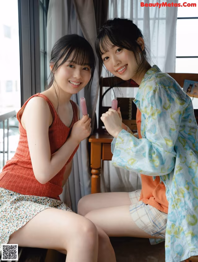 Two young women sitting next to each other on a window sill.