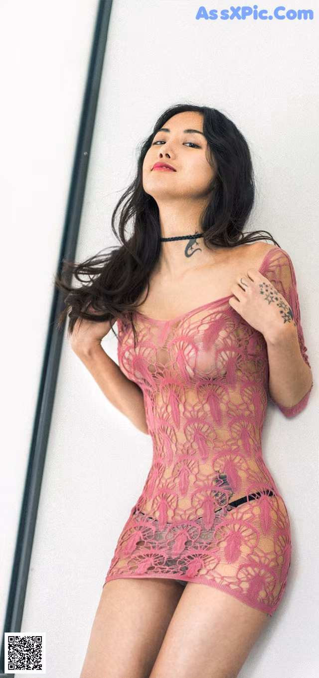 A woman in a pink lingerie leaning against a wall.