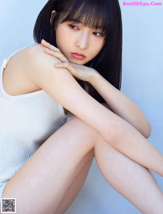 A woman sitting on the ground with her legs crossed.