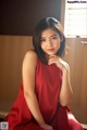 A woman in a red dress sitting on a window sill.