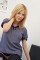 A woman in a blue shirt and black stockings sitting on a chair.