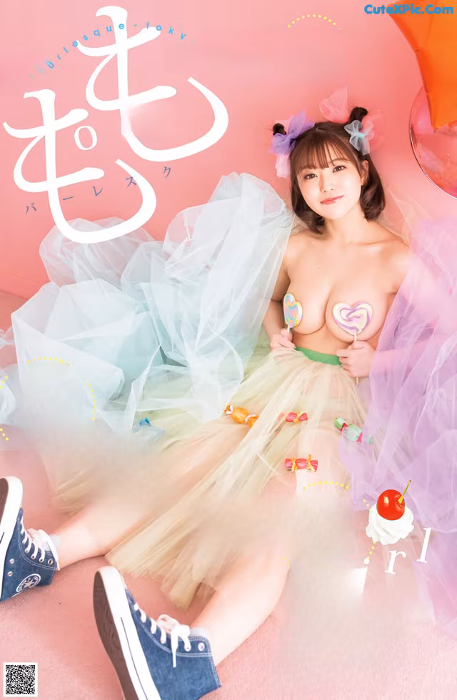 A woman in a tutu sitting on the floor with a lollipop.