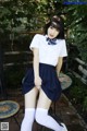 A woman in a school uniform sitting on a table.