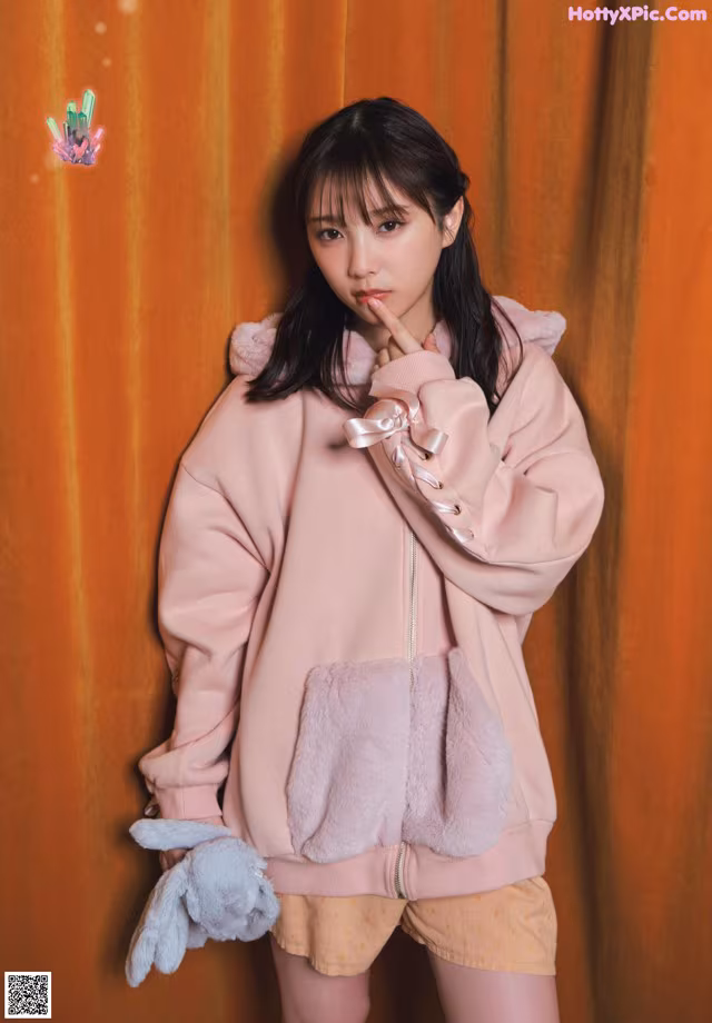 A woman in a pink jacket and shorts posing for a picture.