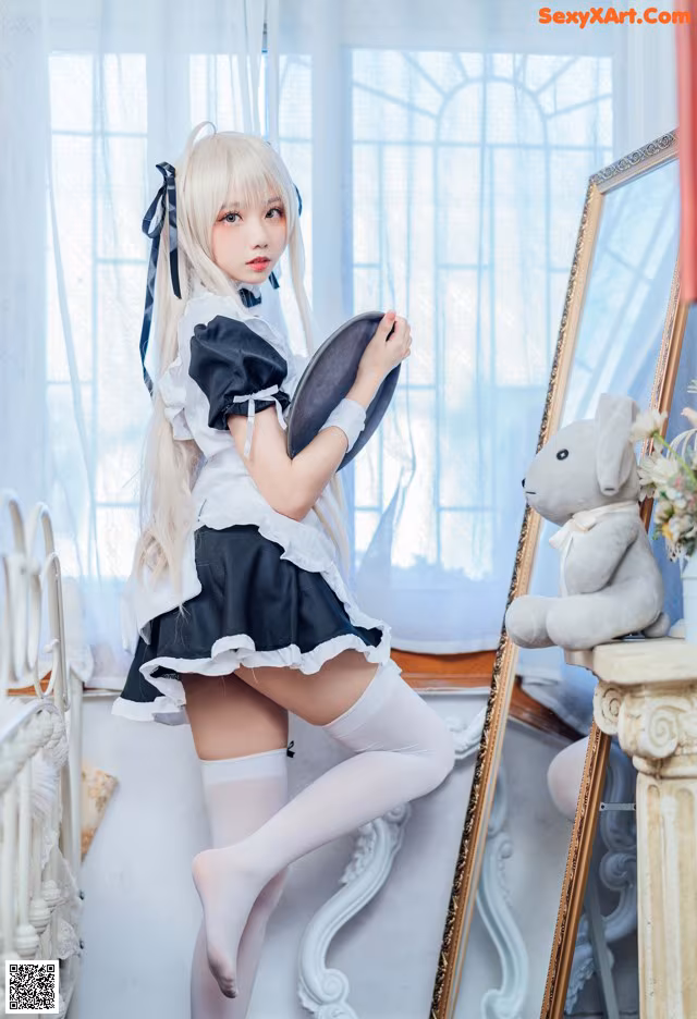 A woman in a maid outfit is posing in front of a mirror.