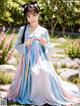 A woman in a blue and pink hanbok is posing for a picture.