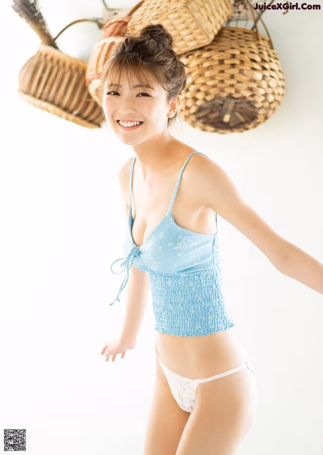 A woman in a blue top and white panties posing for a picture.