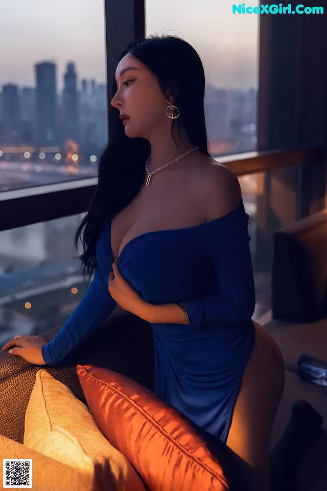 A woman in a blue dress sitting on a couch.