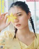 A woman holding a star fruit in front of her face.