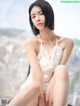 A woman in a white lingerie sitting on a window sill.