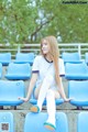 A woman sitting on a blue chair in a stadium.