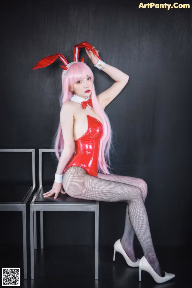 A woman in a red latex outfit sitting on a chair.