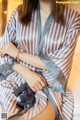 a woman sitting on a bed wearing a striped robe