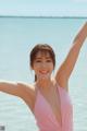 A woman in a pink bathing suit standing in the water.