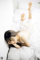 A woman laying on a bed in a white lingerie.